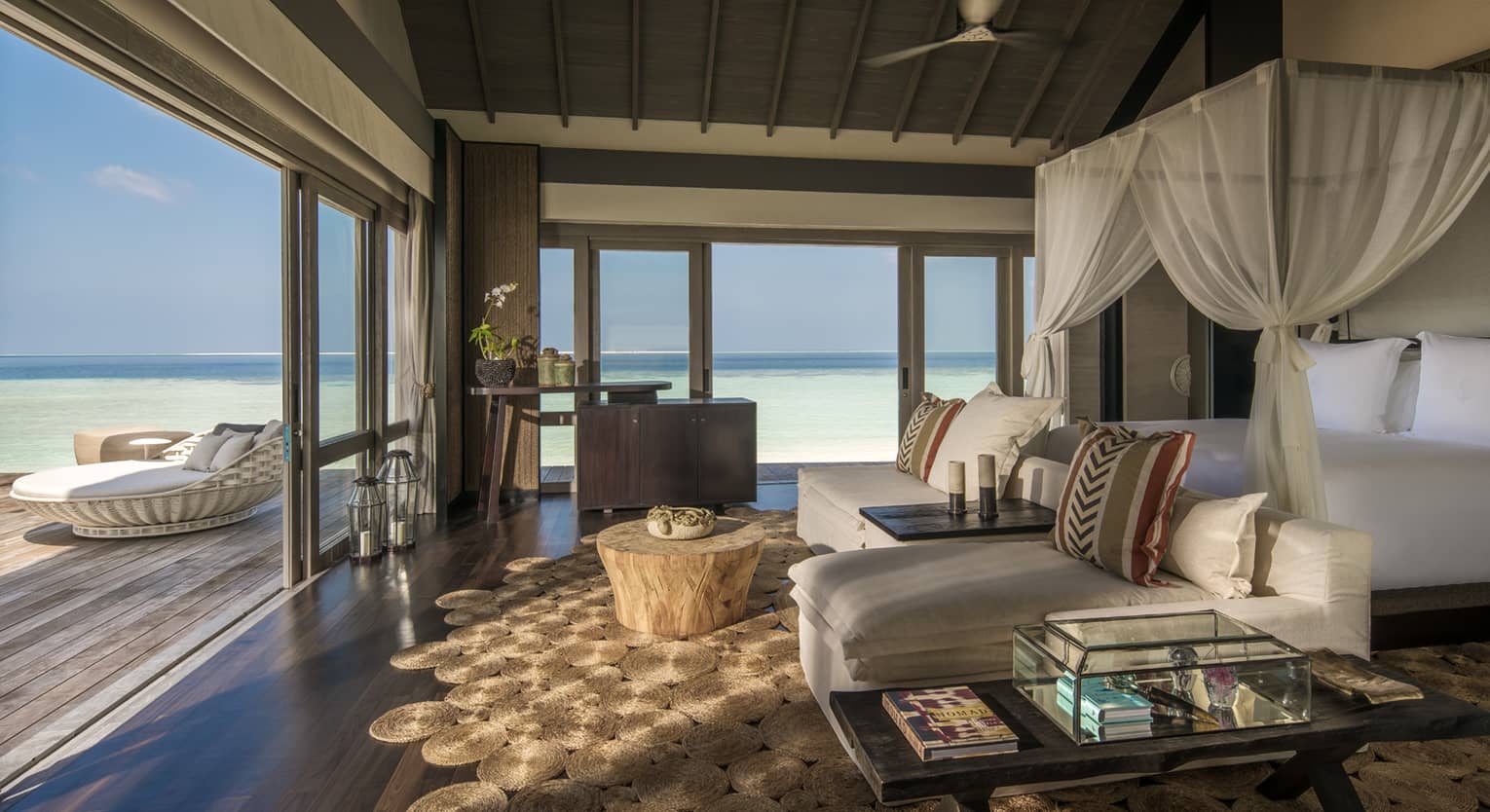Three-Bedroom Beach Villa canopy bed. chaise lounge chairs across from open sliding doors to patio