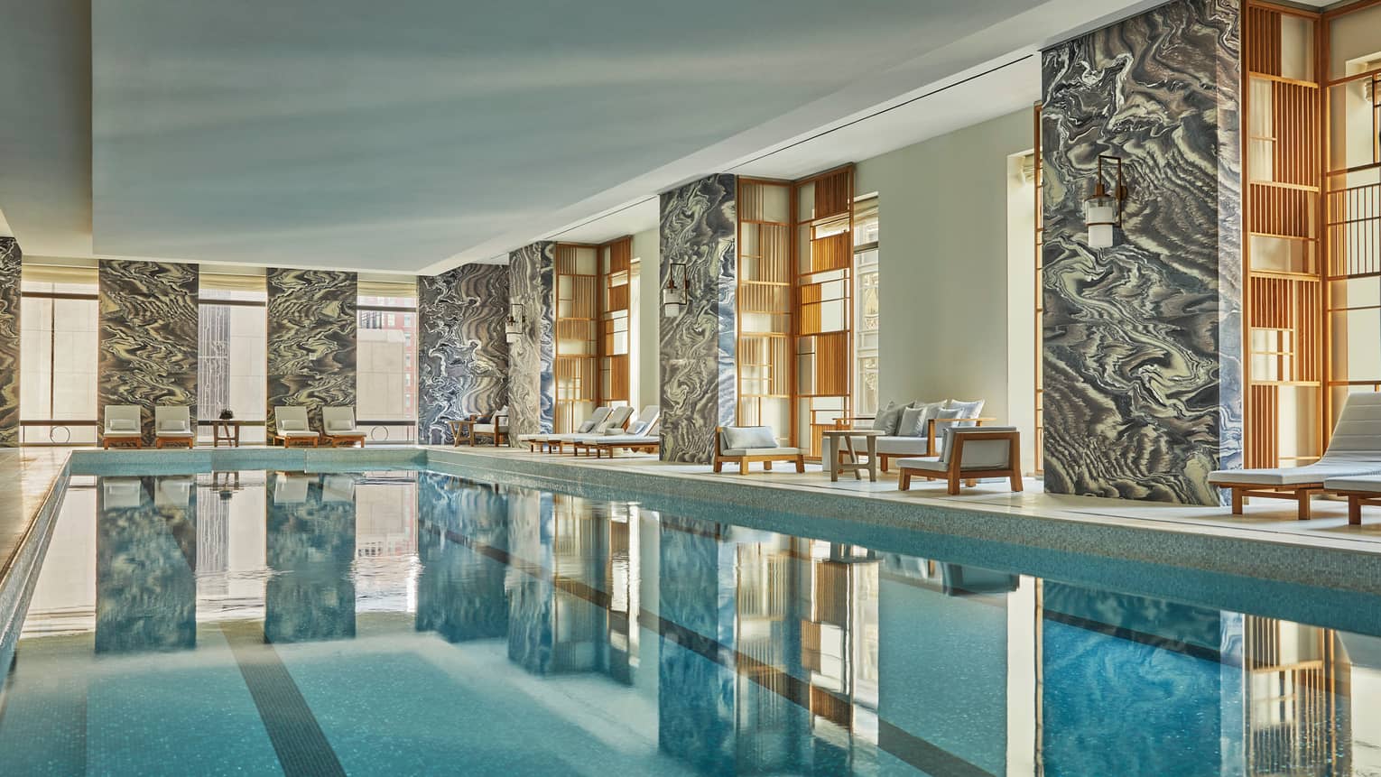 Black-and-white dramatic stone marble pillars, windows around long indoor swimming pool