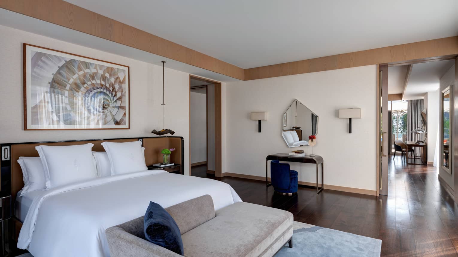 Bedroom with king bed, chaise, vanity, wooden floors
