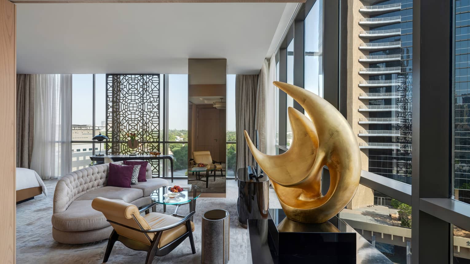 Living area with chaise, leather and wood arm chair, artwork, walls of windows