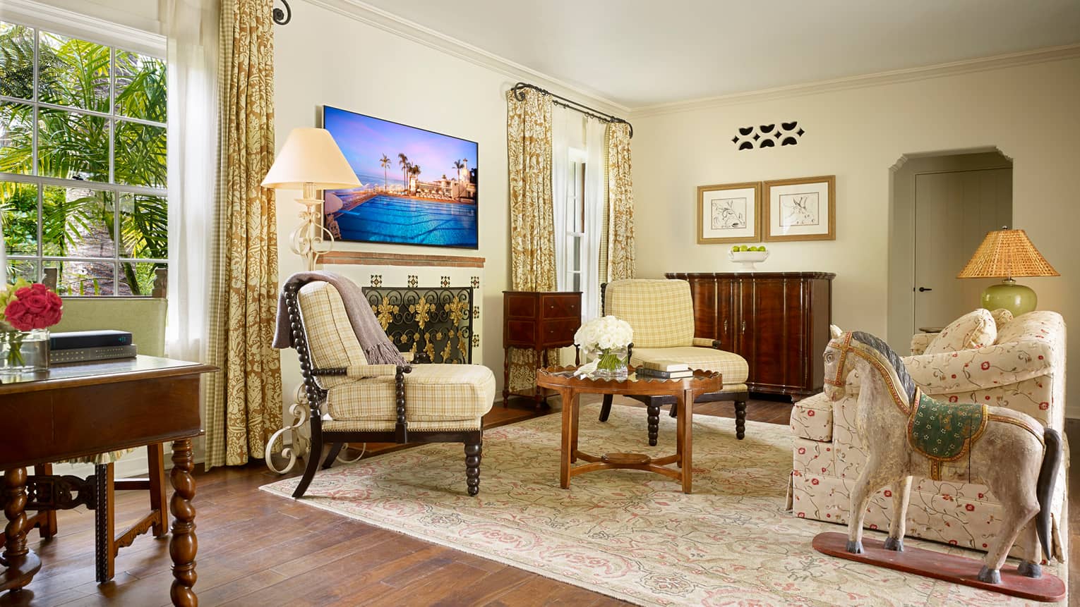 Bungalow Suite sunny living room with yellow plaid accent chairs, floral sofa, rocking horse statue