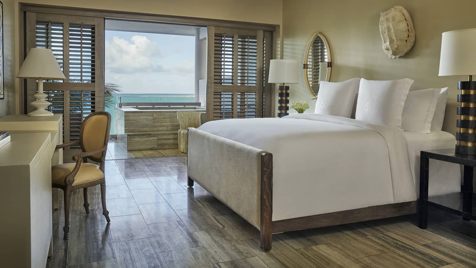 Ocean-View Studio Room bed, desk, bedside lamps, white wall sculpture, patio doors with wood shutters