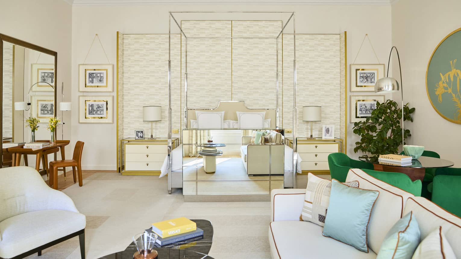Modern luxury hotel suite with metal four-post bed, dining table with four green chairs, and a sitting area with a white sofa and arm chair