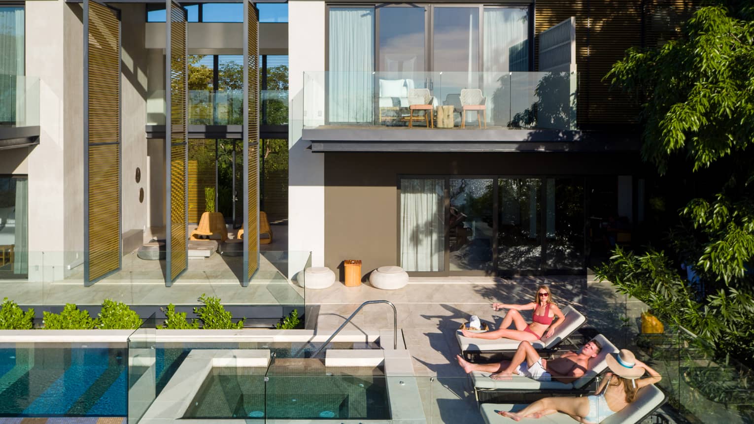 People on lounge chairs by outdoor pool