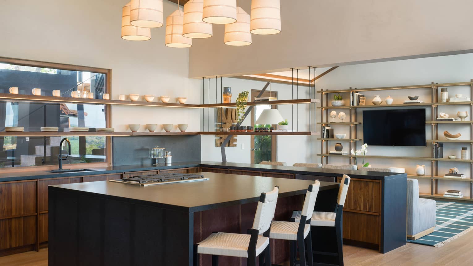 Kitchen with large island, three counter chairs, hanging lights