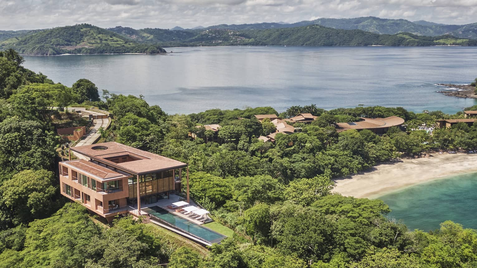 Aerial view of private villa with long rectangular pool near a beach
