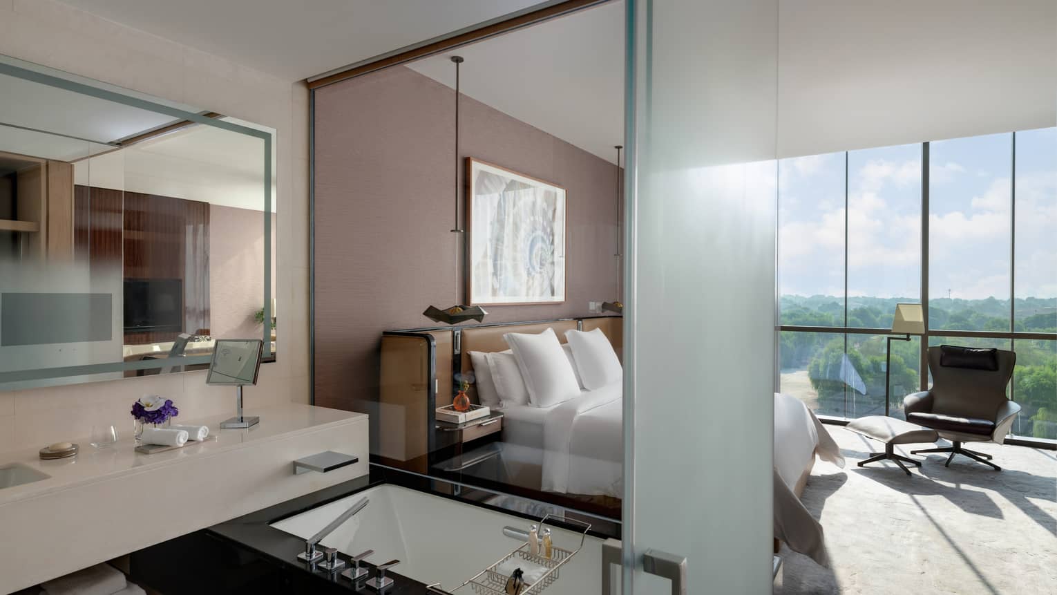 Bedroom with wall of windows, king bed, open bathroom with tub
