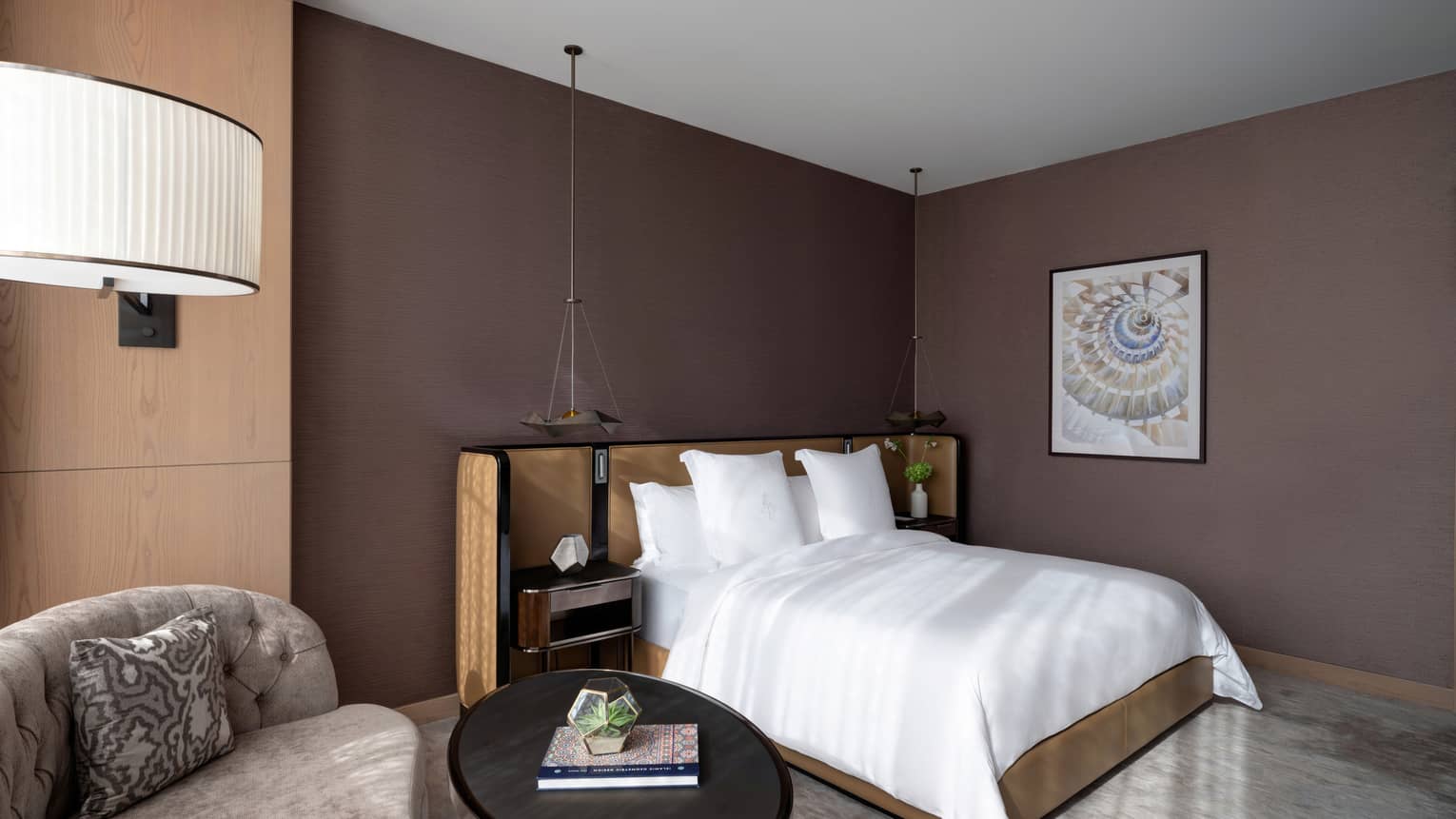Bedroom with brown walls, white king bed, chaise by the window