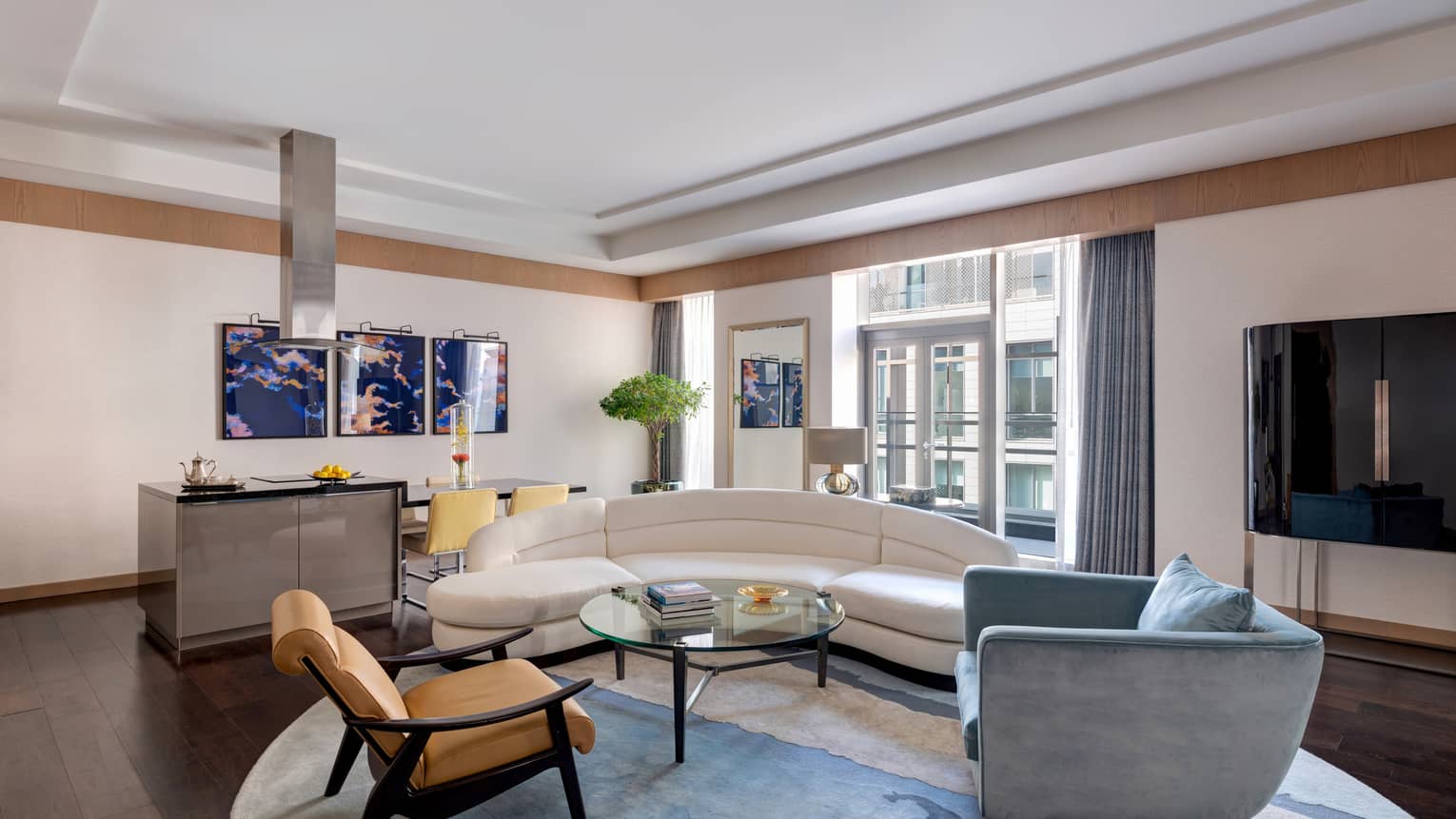 Living room with white curved sofa, blue arm chair, leather chair, dining area