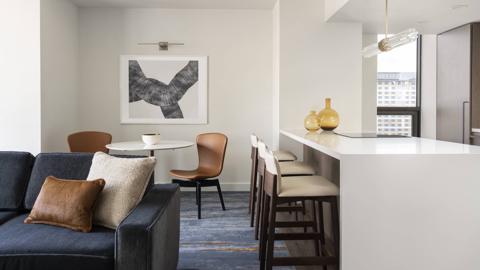 One-bedroom Residential Suite living area, dining area and kitchen with dark blue accents and bar stools