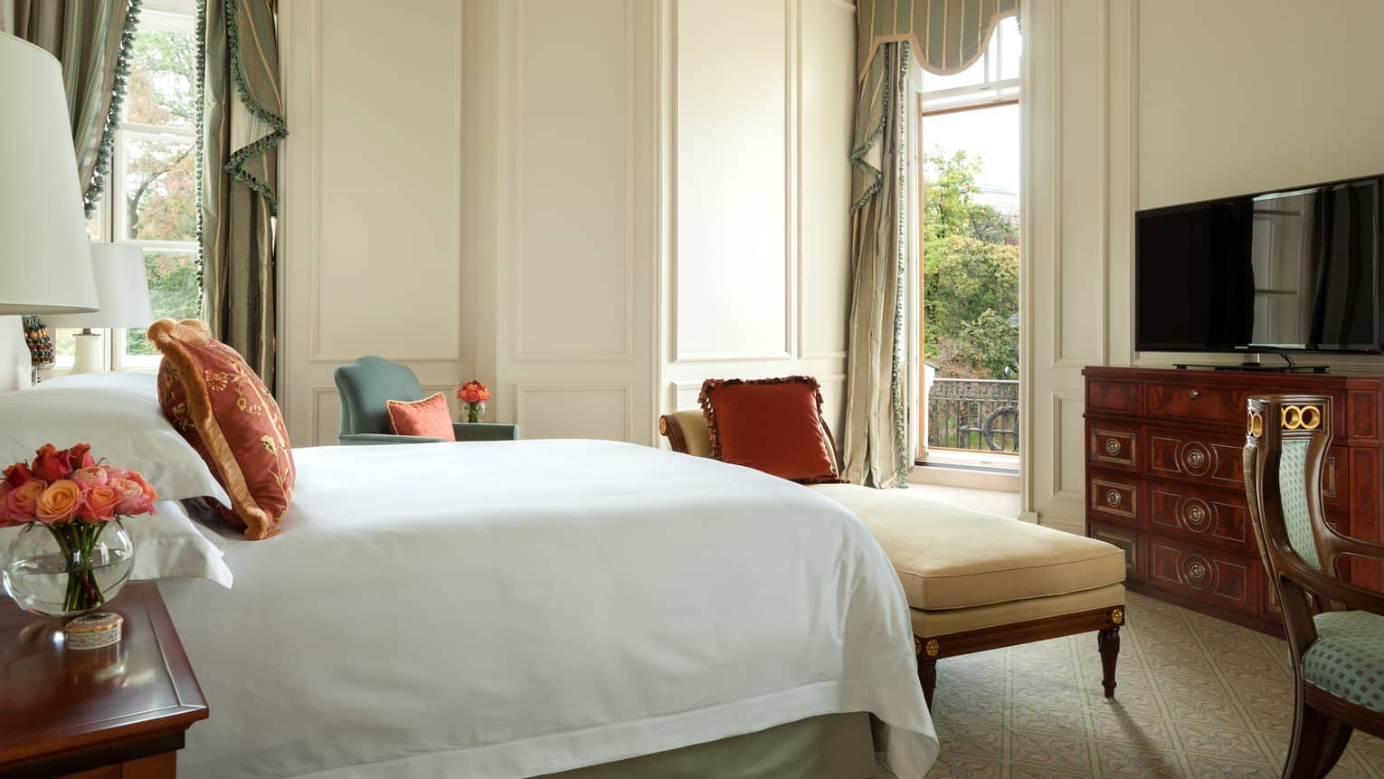 Noble One-Bedroom Suite side of bed with white linens, bench in front of dresser, open door