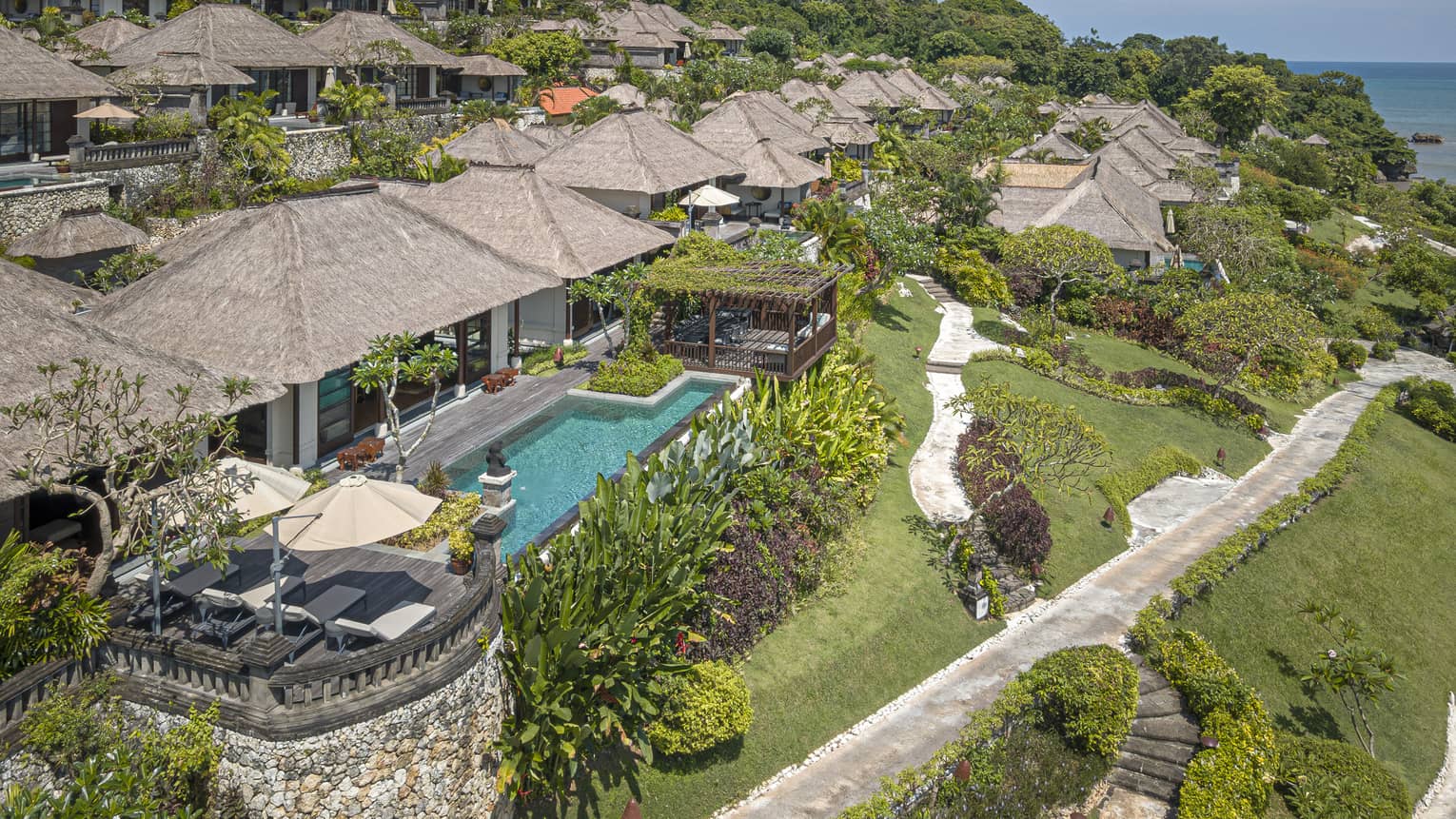 Aerial view of Royal Villa with pool, rolling green hills, ocean views
