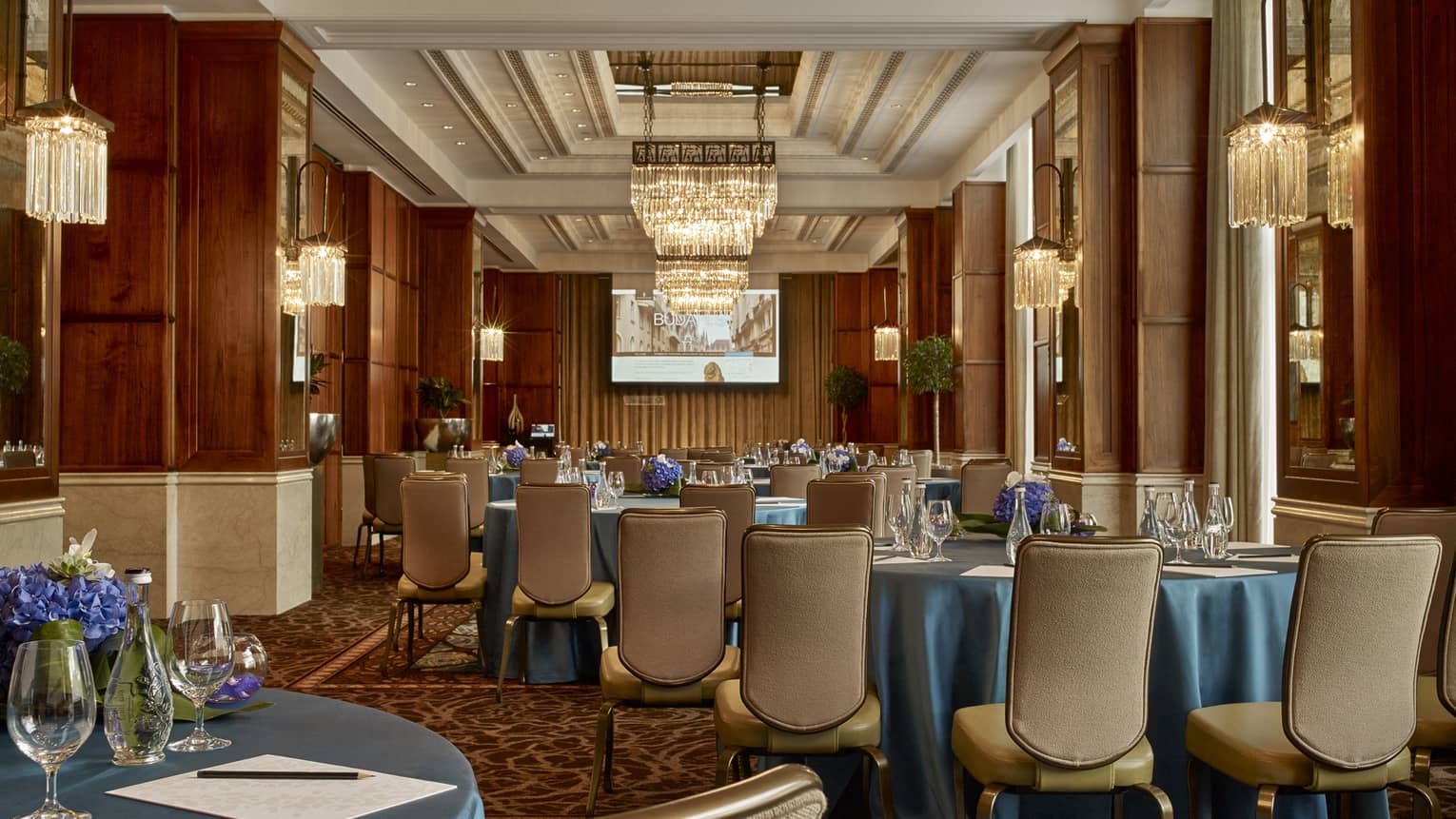 Gresham Room Art Nouveau-style ballroom tables with blue satin tablecloths, leather dining chairs, chandeliers