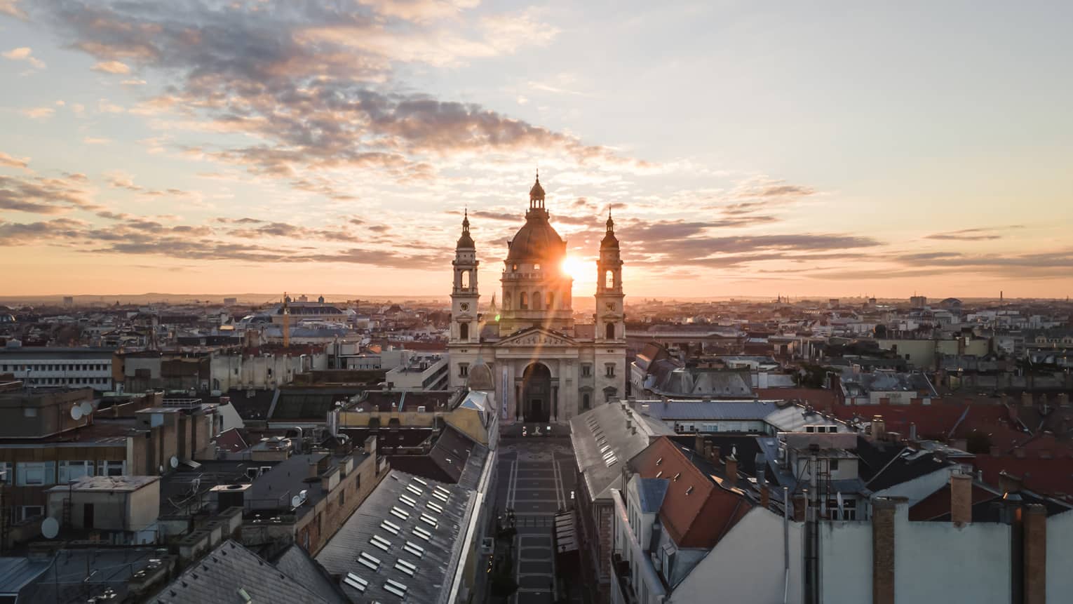 Historic domed cathedral with twin towers at sunrise above city rooftops