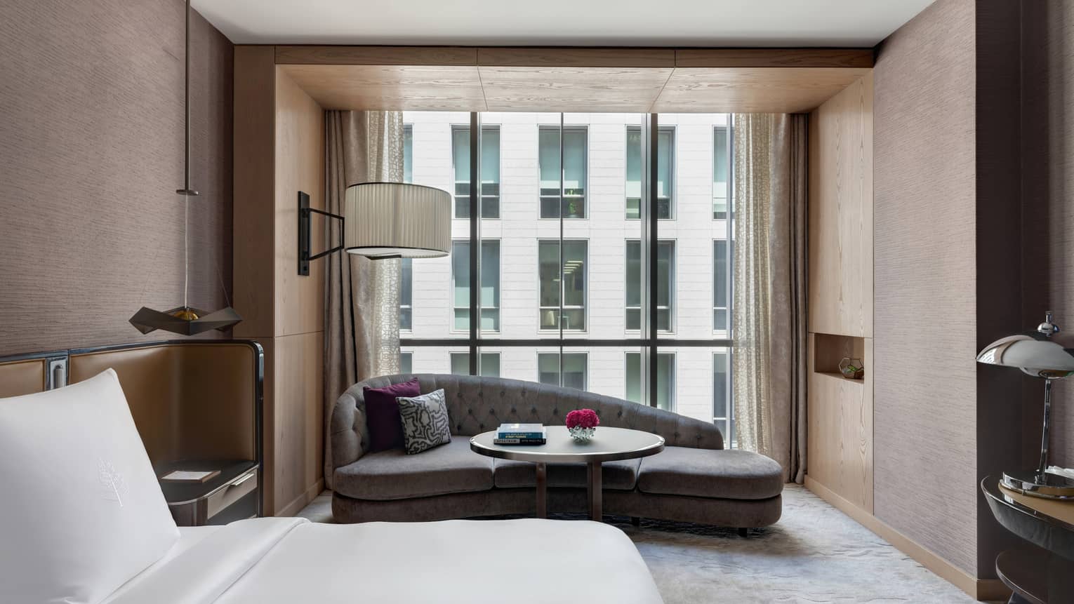 Bedroom with mauve-coloured walls, king bed, chaise lounge by window