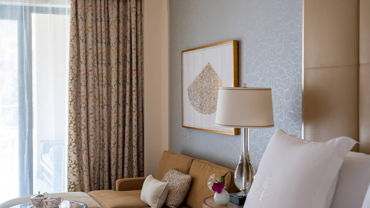 Bed next to a light brown sofa and glass coffee table, sliding glass doors