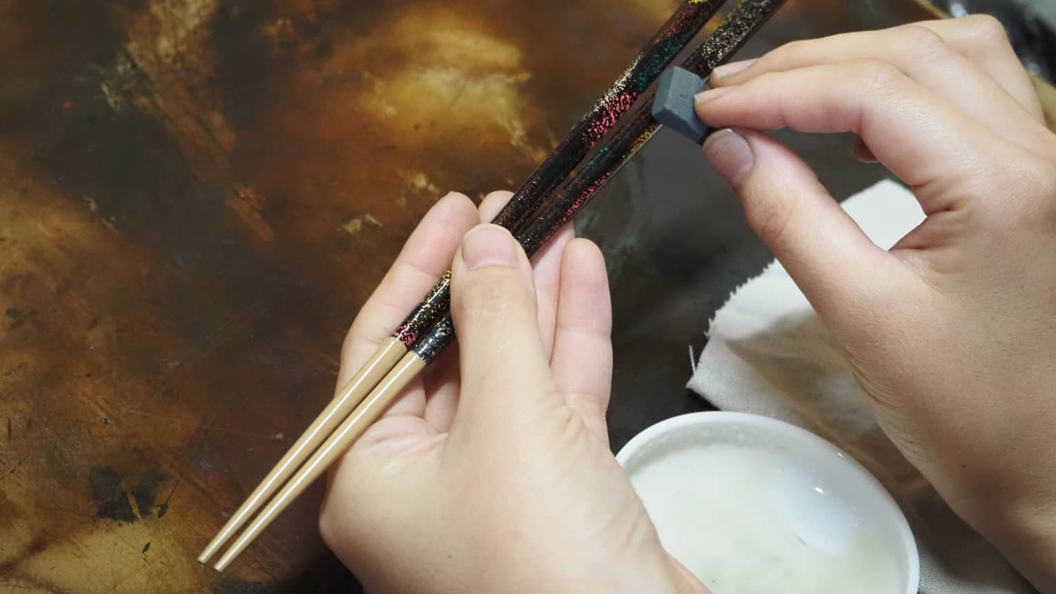 Hands apply Japanese lacquer to customize artisan chop sticks
