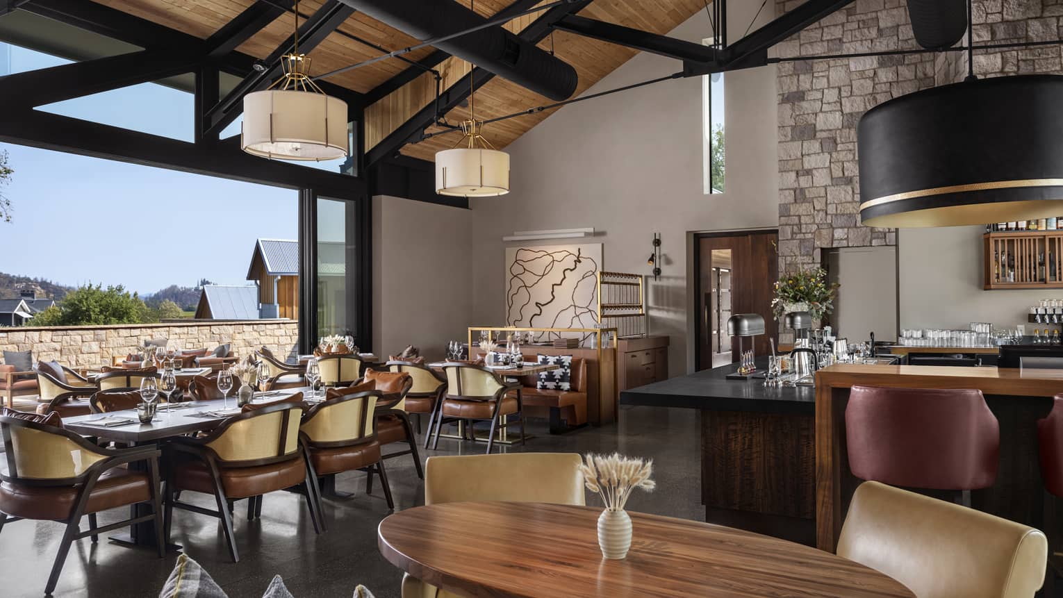 Restaurant with vaulted wooden ceiling, wooden tables and leather chairs, opens to the outdoors