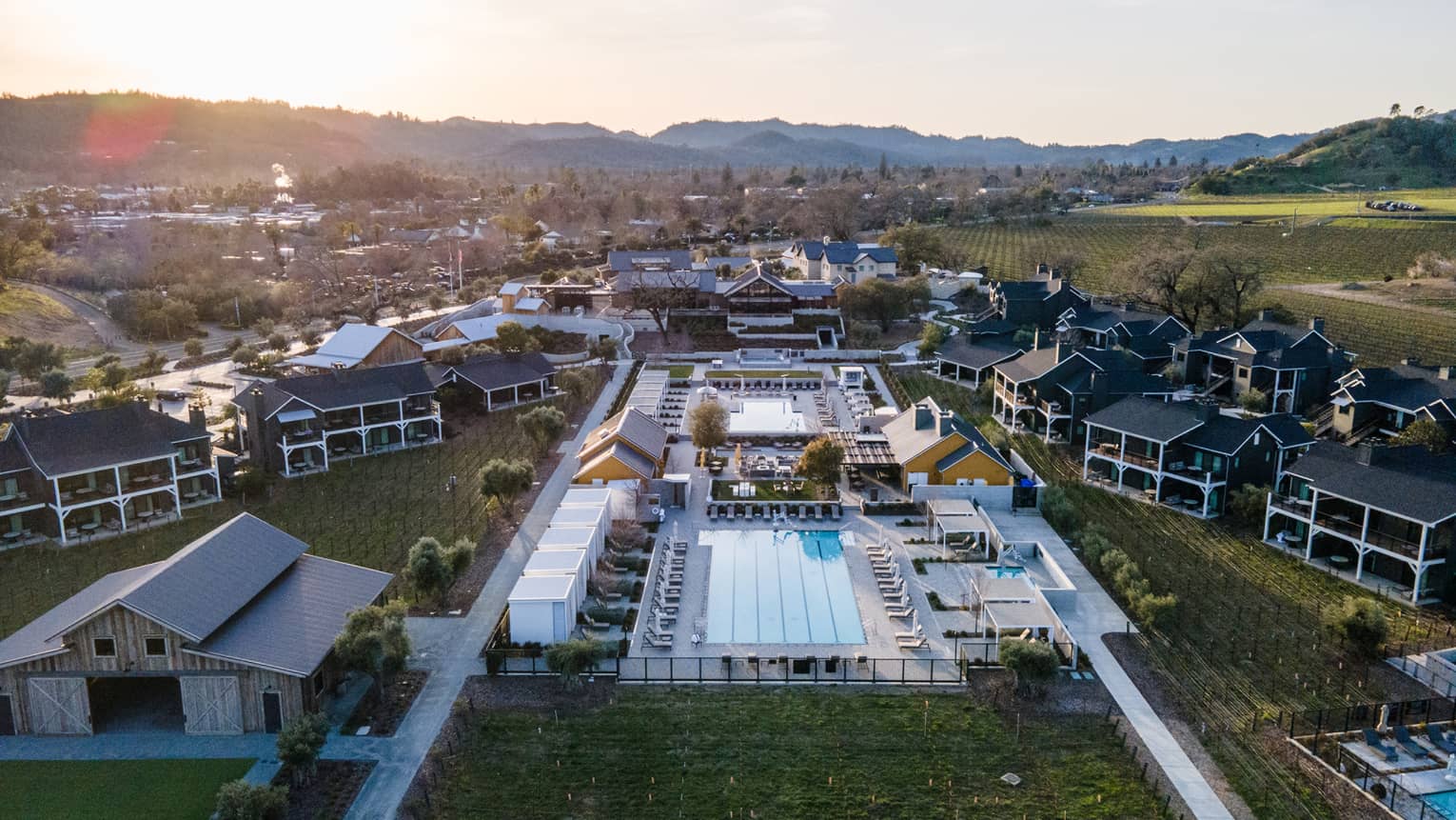 Aerial view of residences, land, trees and a pool.