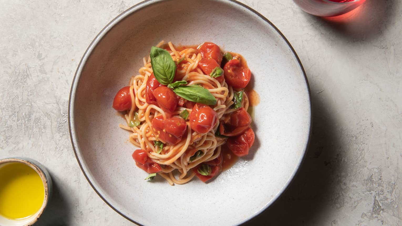 Spaghetti with tomatoes and basil on a white plate.