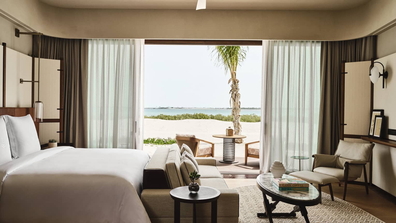 Contemporary bedroom with king bed, sofa, coffee table, arm chair and large walk-out, sea-view terrace