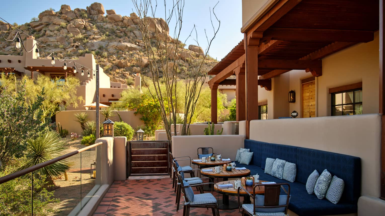 Outdoor terrace with booth seating and chairs and a view of the mountains.