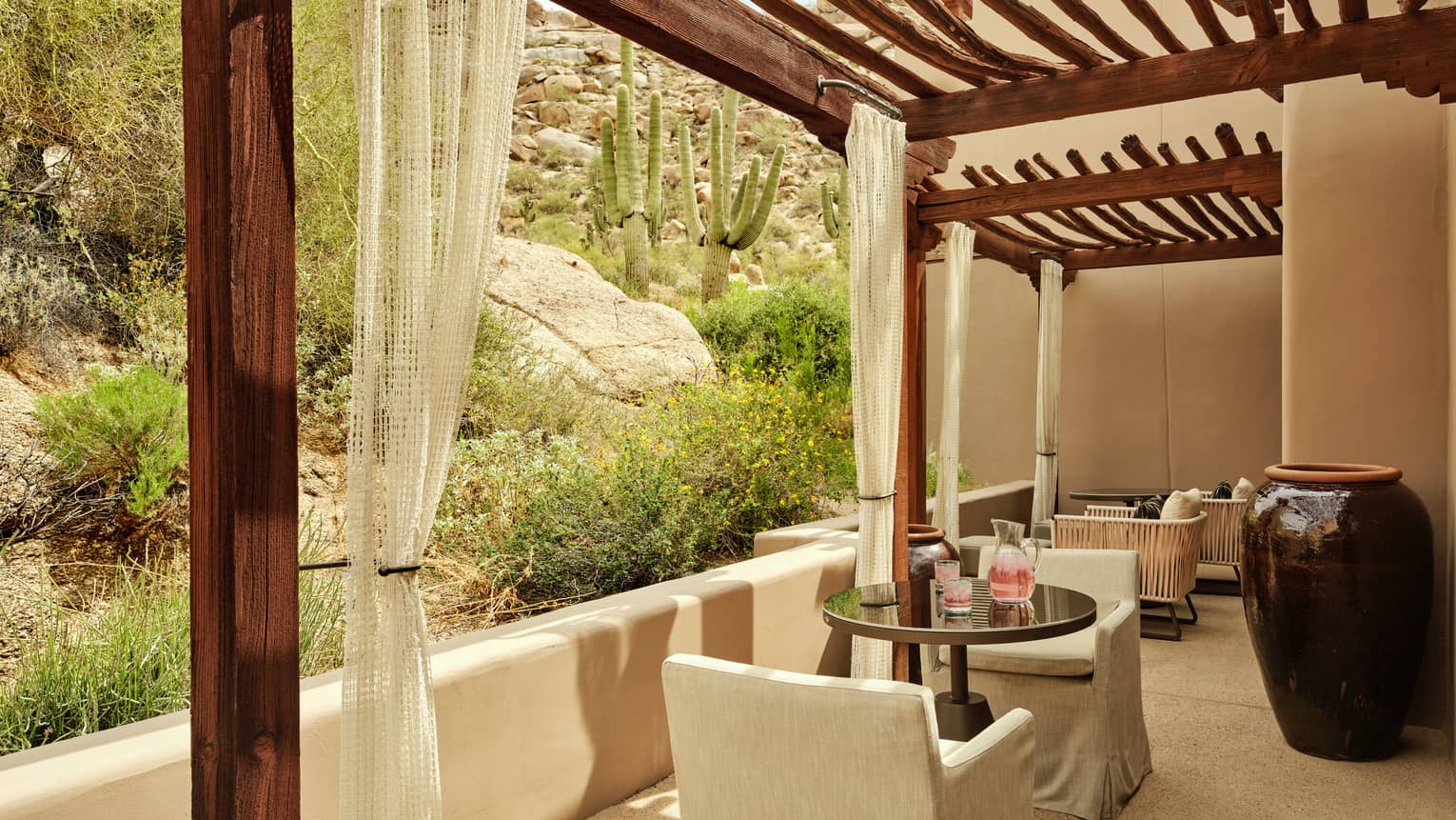 Private terrace featuring a wooden pergola, a table and two chairs and desert garden surroundings