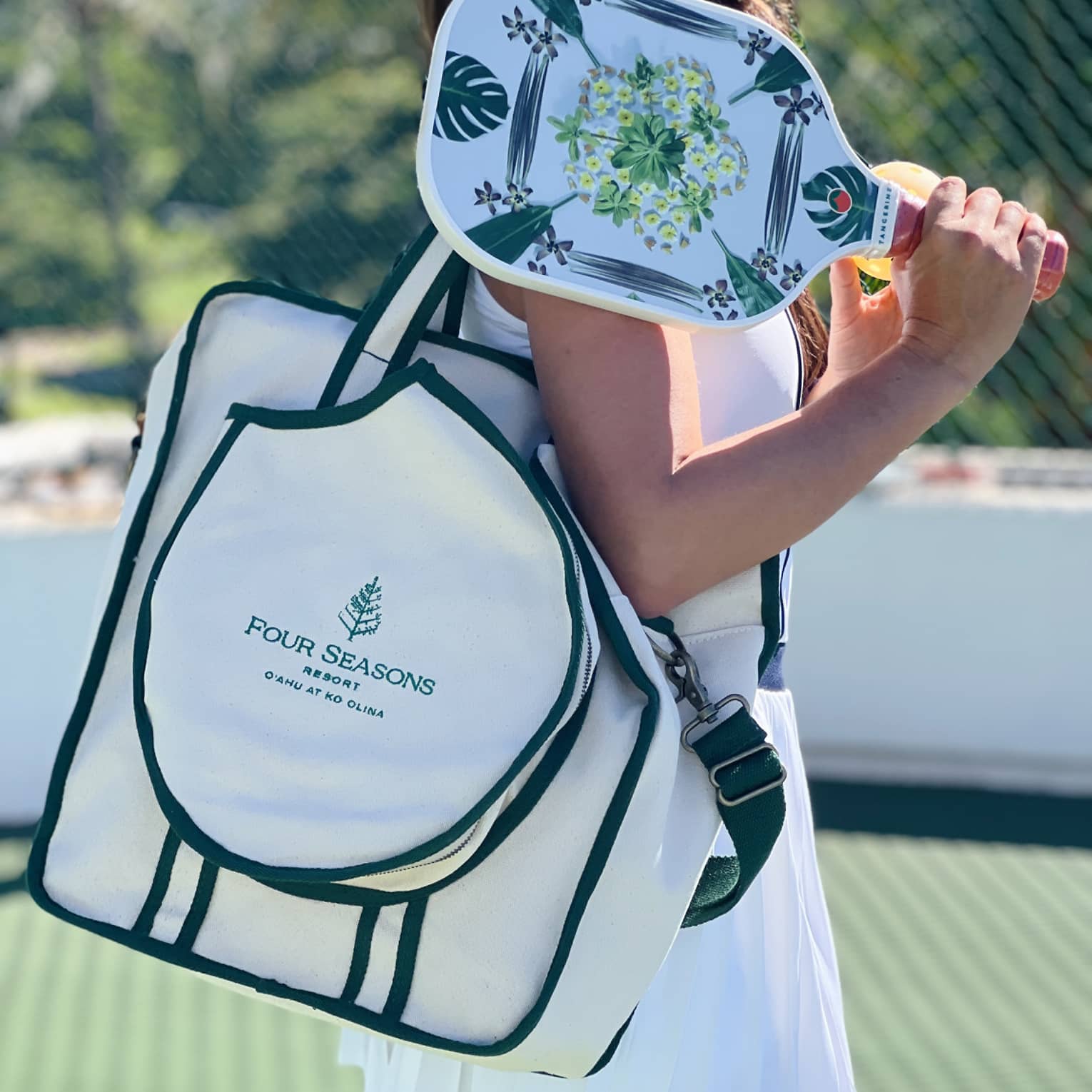 Woman holding pickleball paddle and Four Seasons bag