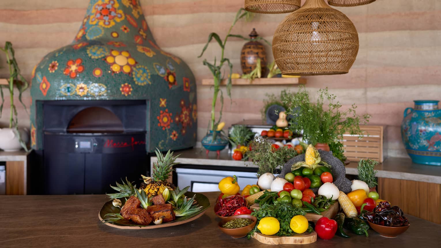A kitchen with colourful mosaic wood-burning oven, and fresh fruit and vegetables on the table