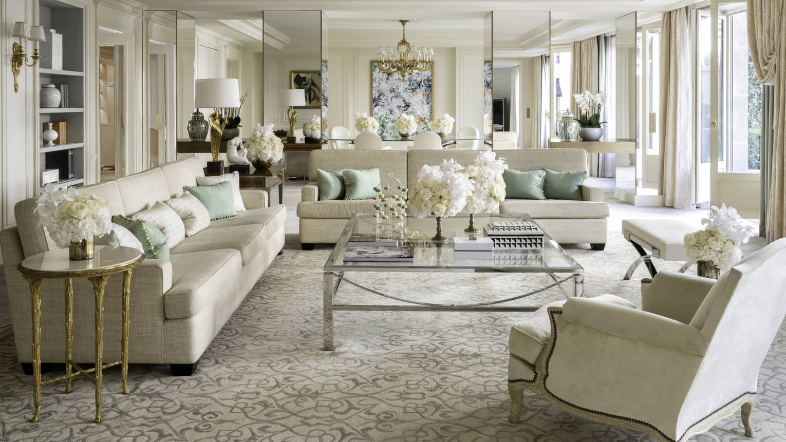 Royal suite with two couches, an armchair, coffee table, cream & teal accents, natural light 