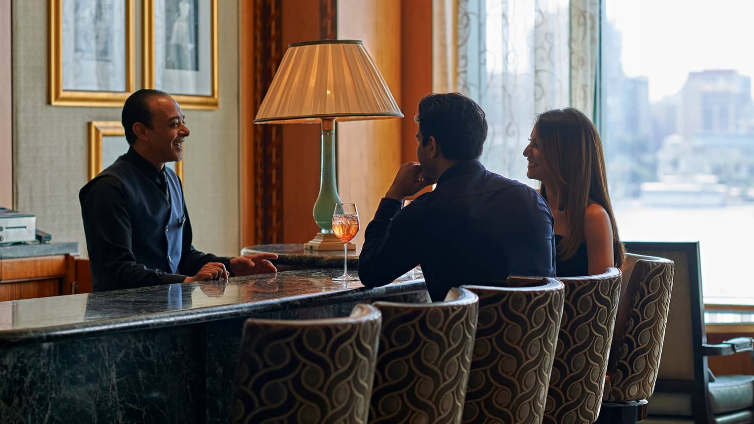 A couple enjoying cocktails at a bar with a city view
