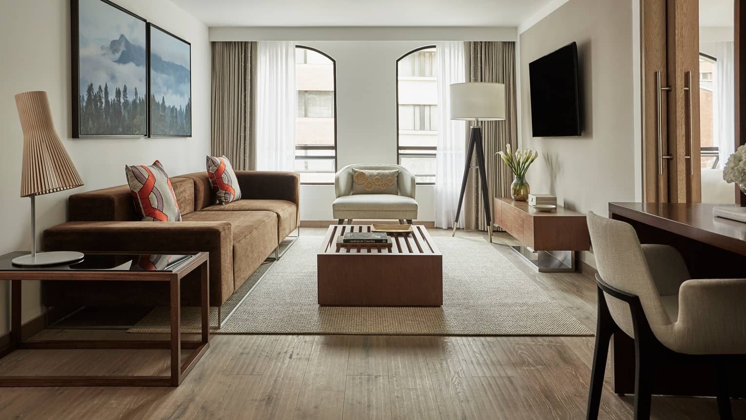 Four Seasons Executive Suite light-filled living room with brown sofa, white chairs, wood tables