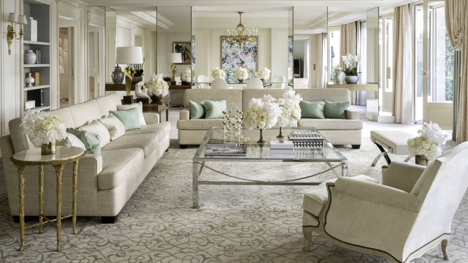 Royal suite with two couches, an armchair, coffee table, cream & teal accents, natural light 