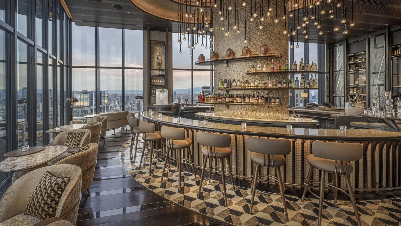 Glamorous indoor hotel bar with curved bar, high-top stools and modern hanging lights, Bar Bota at Four Seasons Hotel Osaka