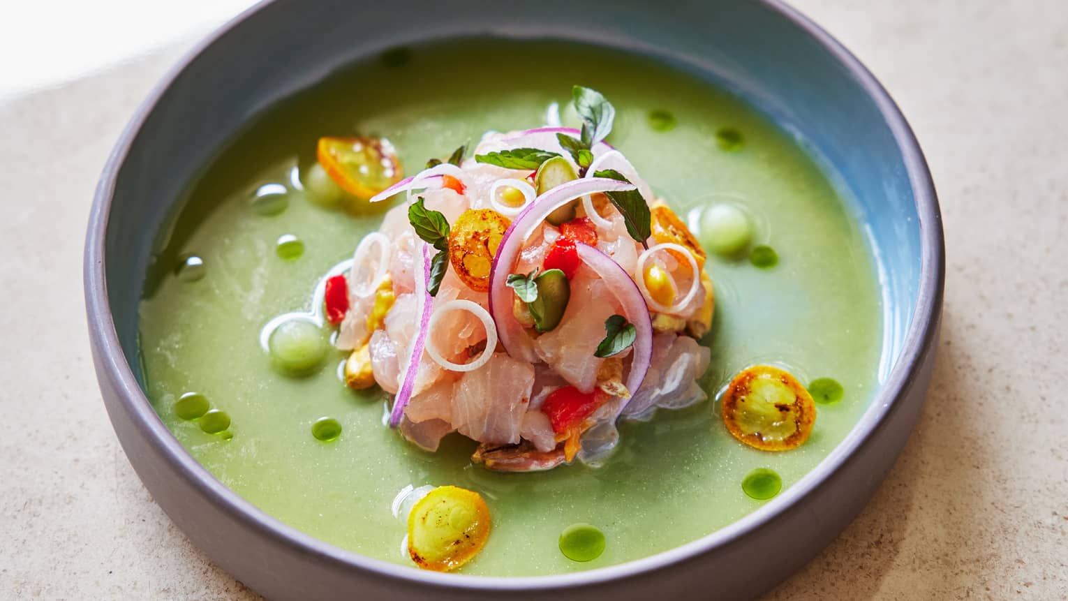 Food in a green sauce in a grey bowl.