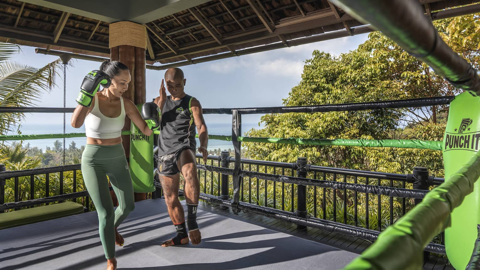 Muay Thai trainer teaches woman in outdoor ring