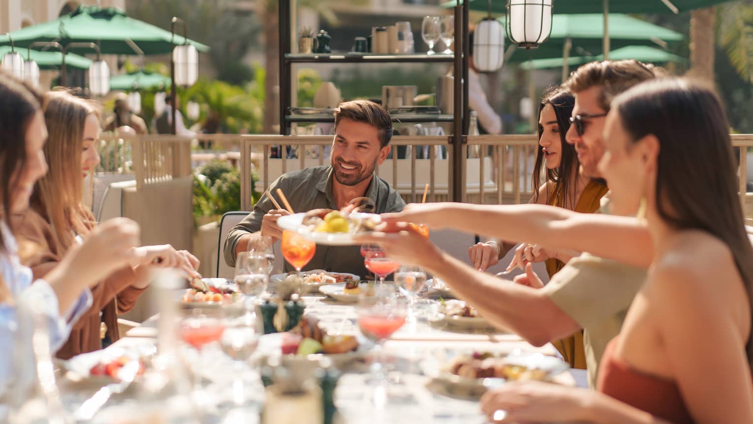Six people sit at an outdoor table for brunch on a sunny day