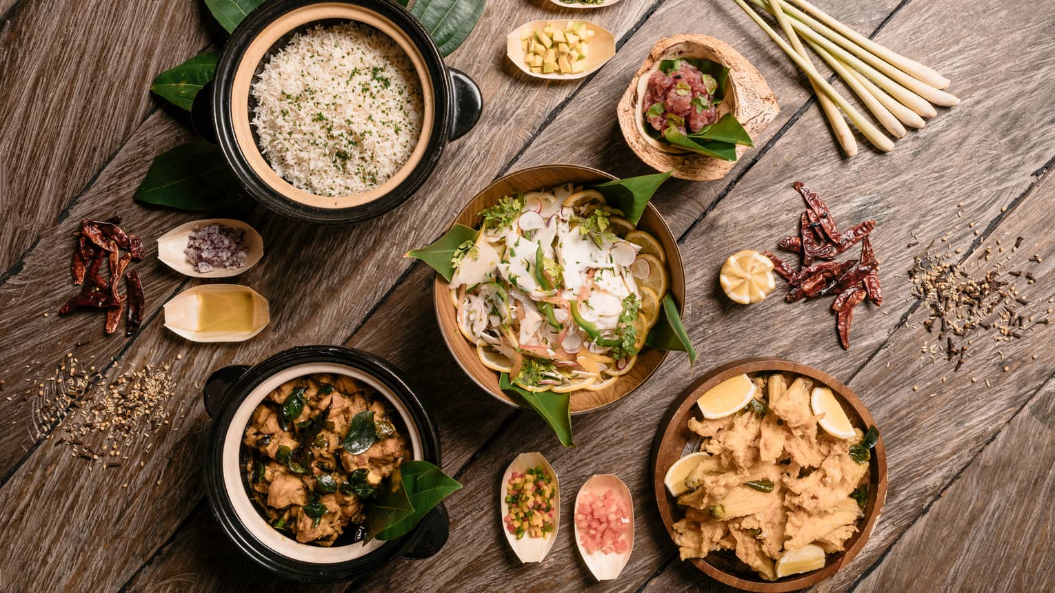 Aerial view of rustic wood table with bowls of gourmet rice, salads and entrees 