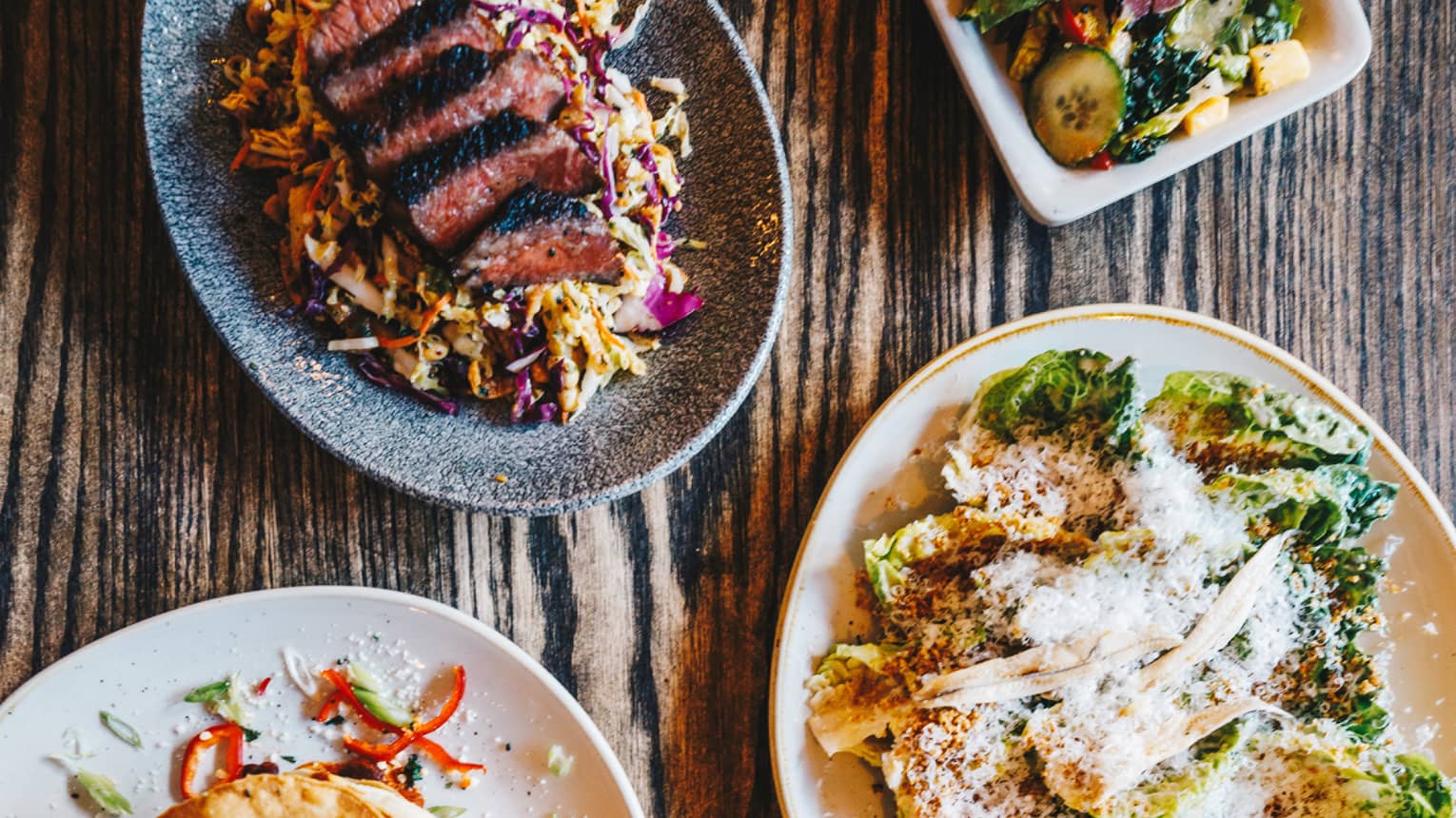 Aerial view of colourful assorted meals on top of a rustic wooden table