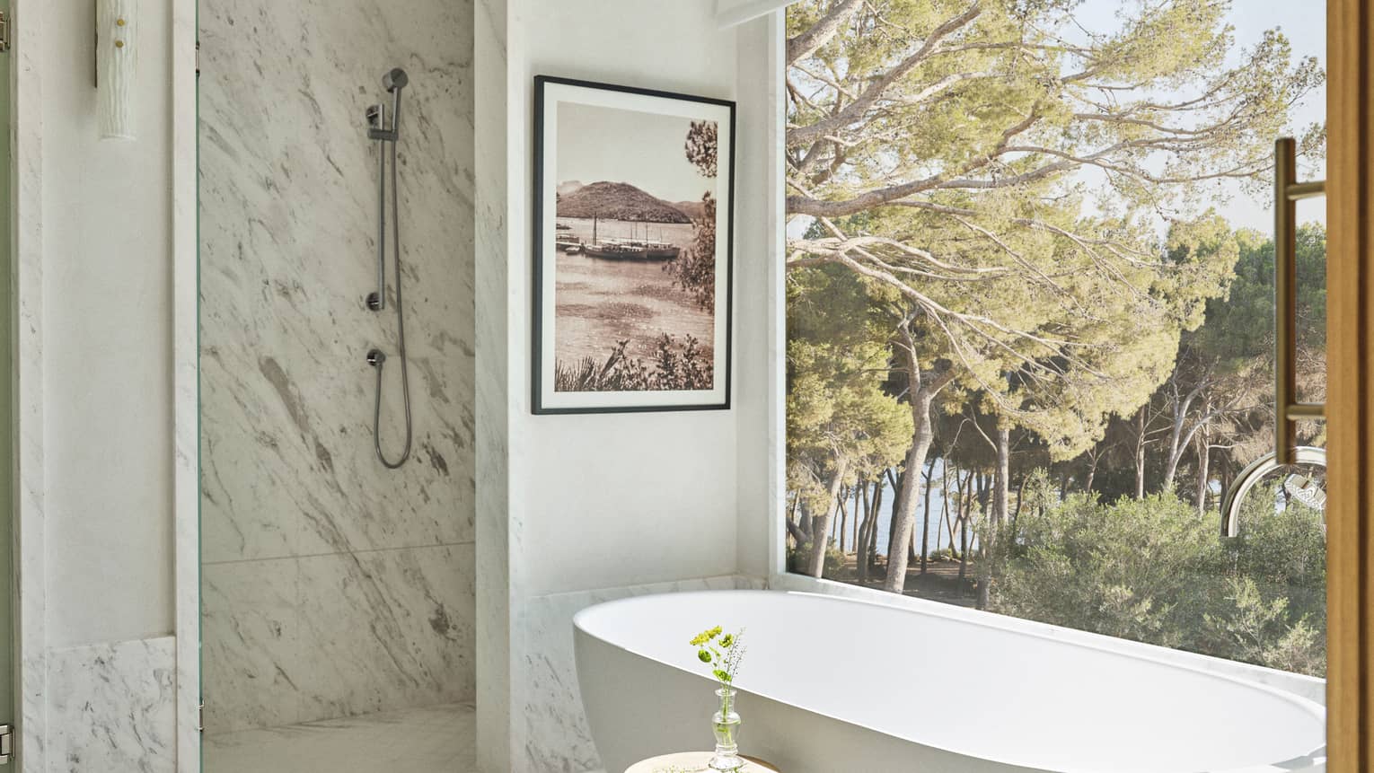 Luxury marble bathroom with standalone tub next to large picture window and pine view at Four Seasons Resort Mallorca