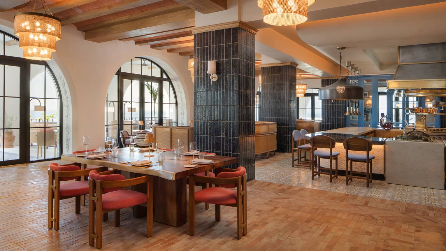 Interior of a restaurant with tall, wood-beamed ceilings, large cylindrical light fixtures and spread out tables and counter seating