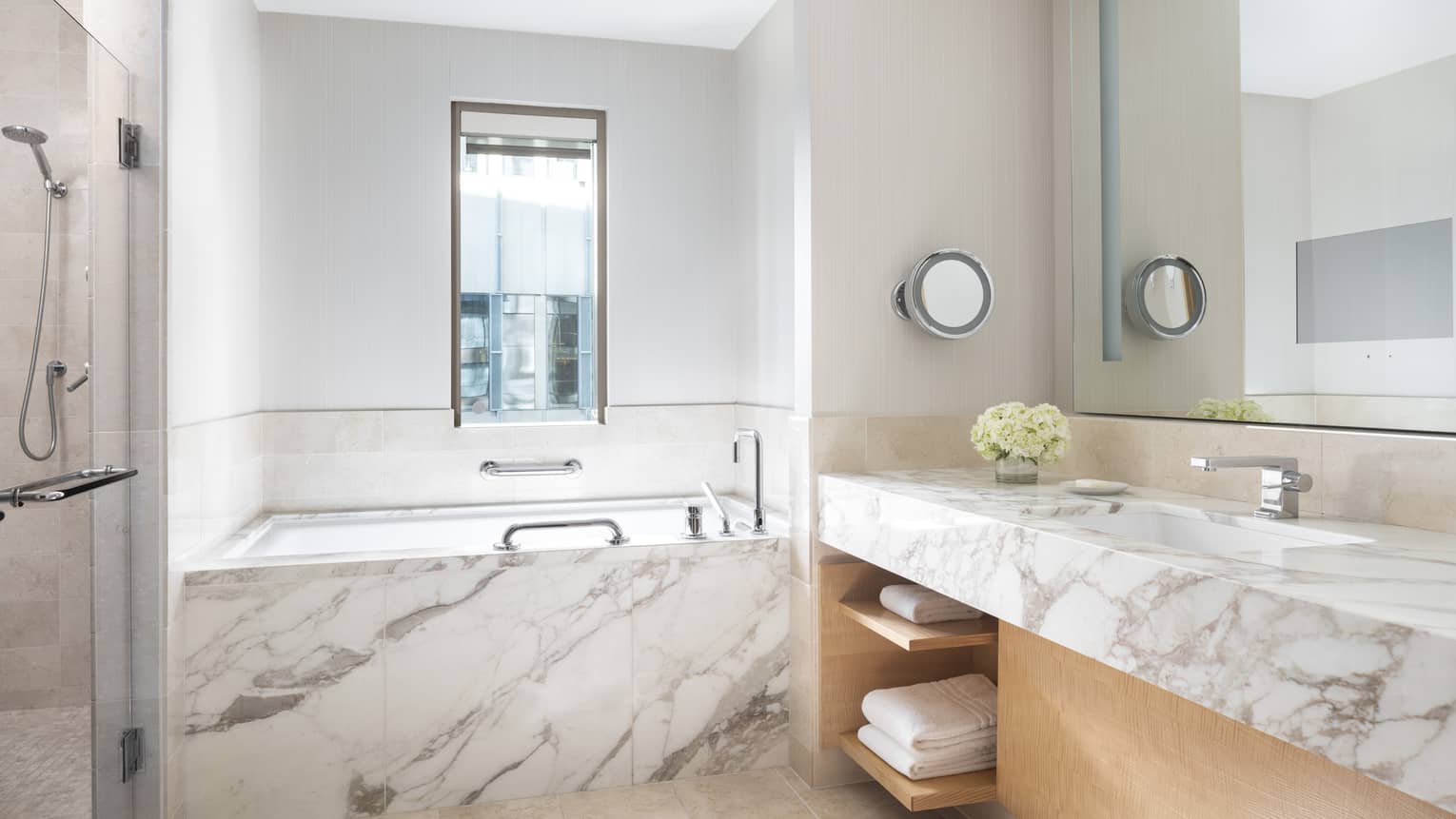 Marble counter and a marble bathtub gleam in a bathroom