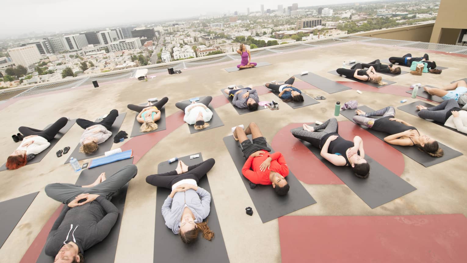 People lay on mats in yoga fitness class on rooftop helipad 