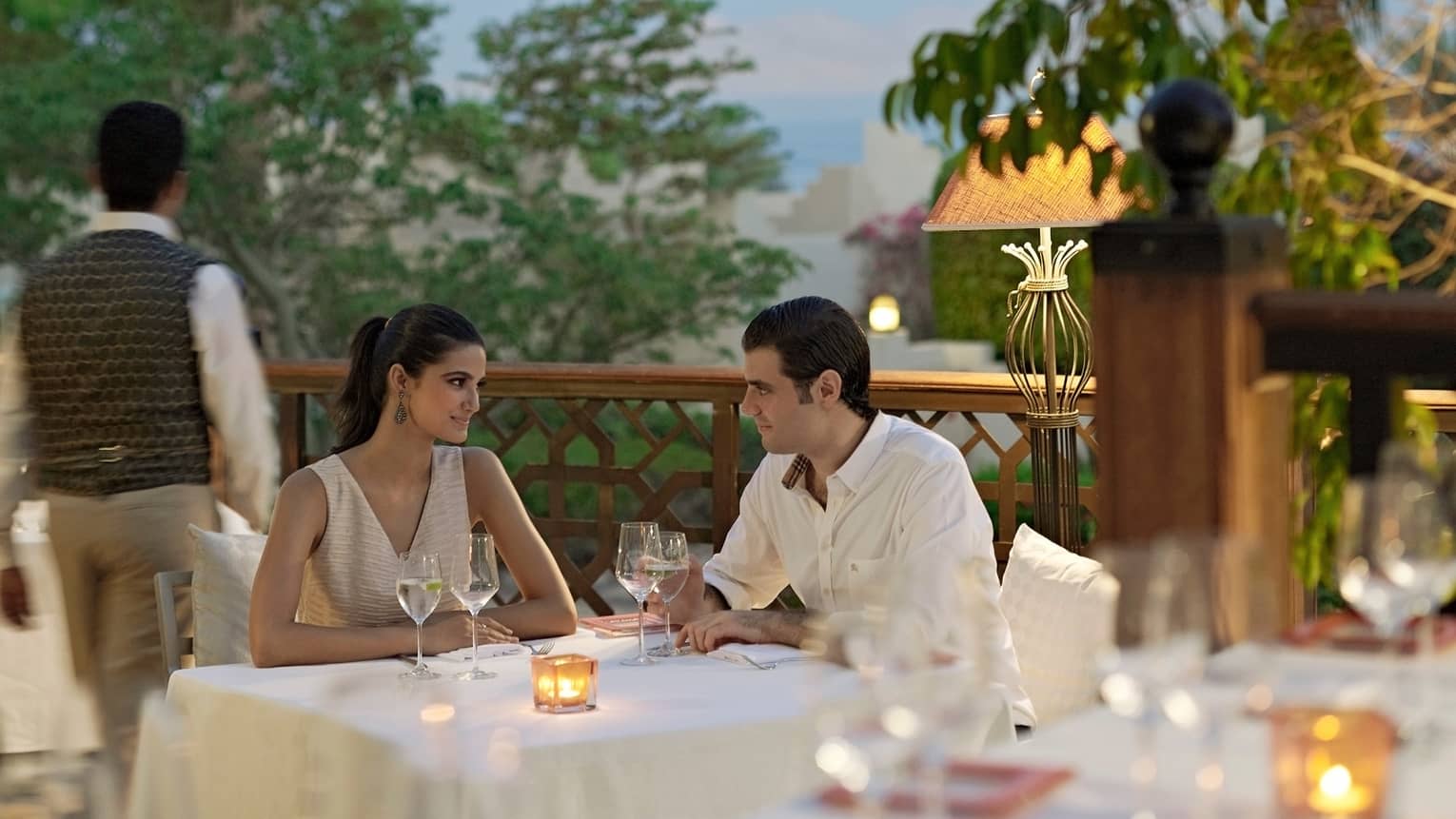 Man and woman at formal dining table on patio at night