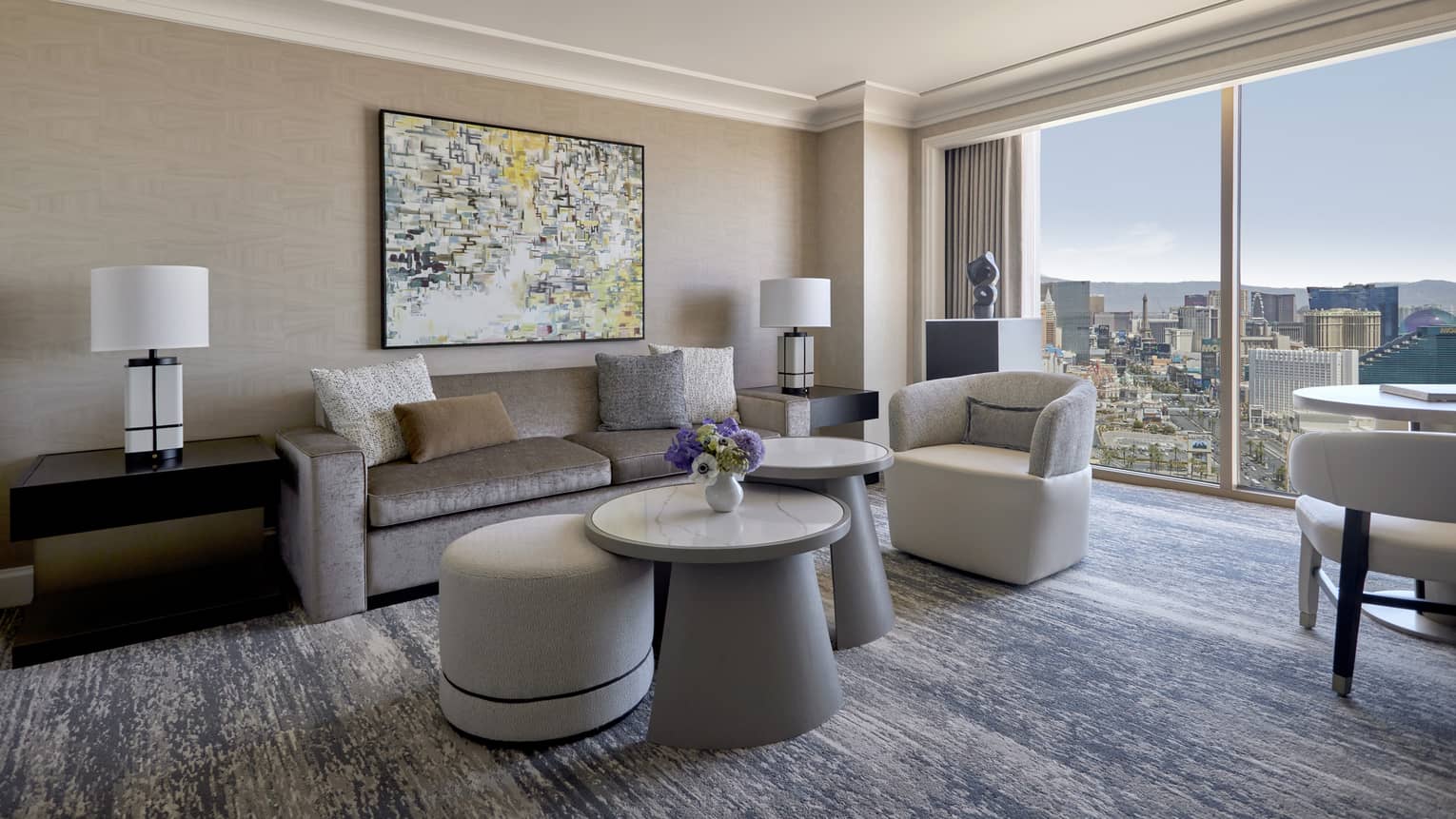 A sitting area with large window, sofa, coffee table, chairs, and small table.