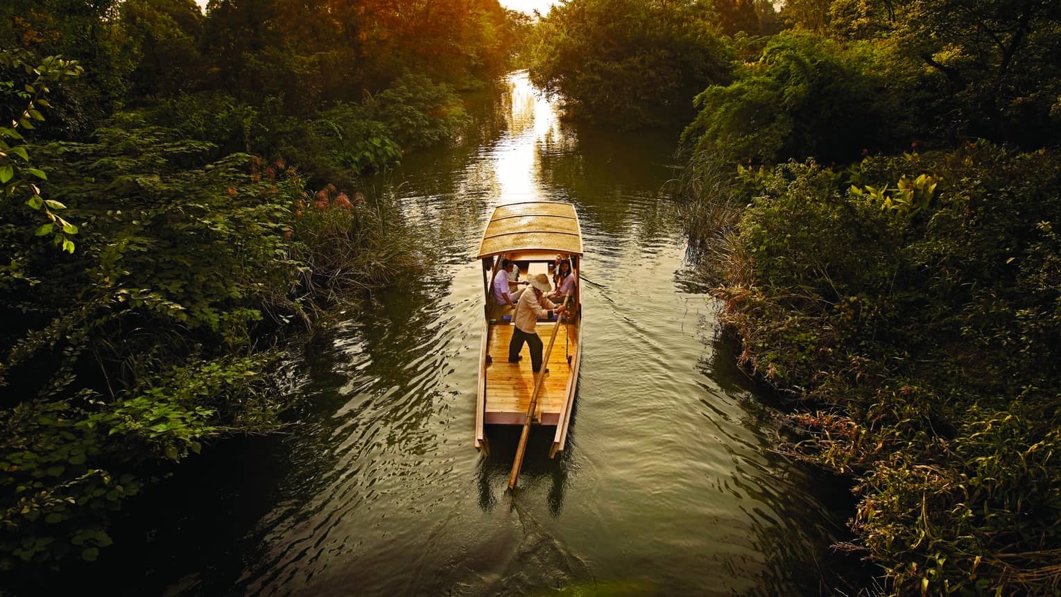 Traditional Chinese wooden boat sails down river in Xixi Wetland National Park