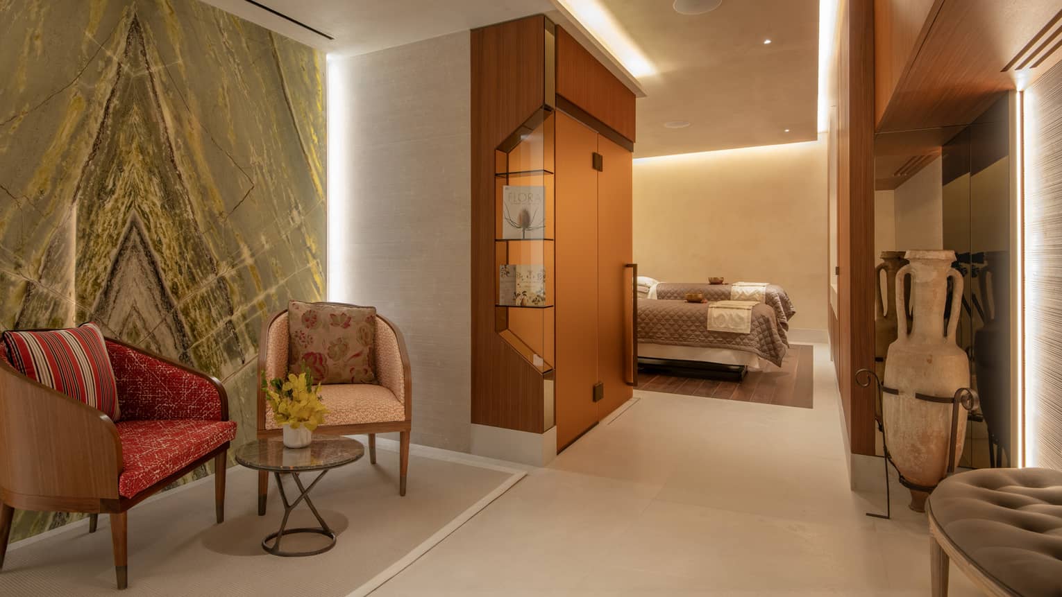 Spa seating vignette against marble wall leading to couples? treatment room with two spa tables