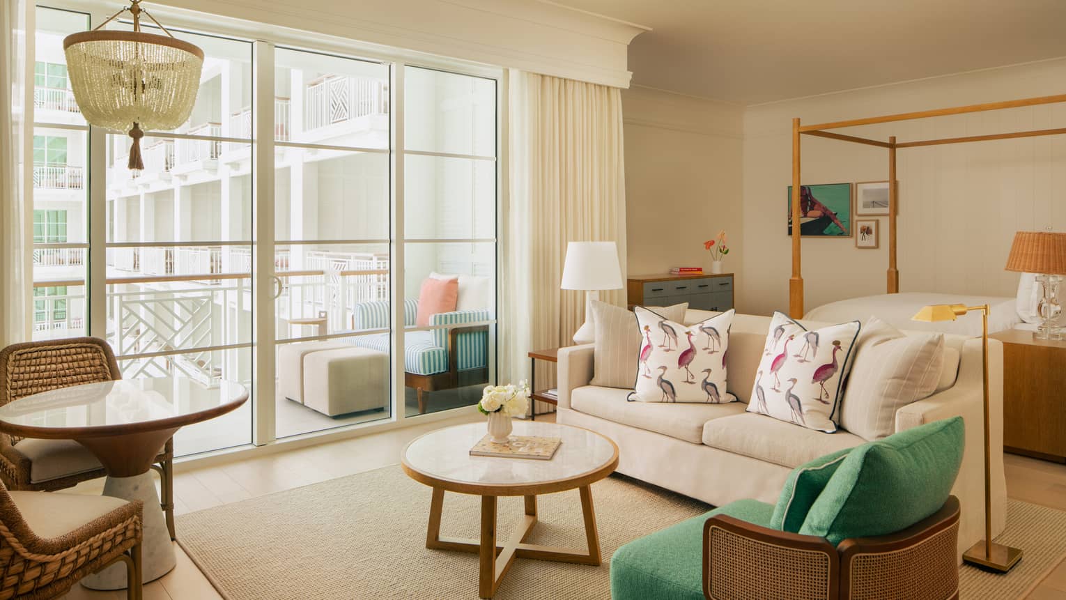 Hotel studio suite with four-post bed, sofa, arm chair and walk-out balcony