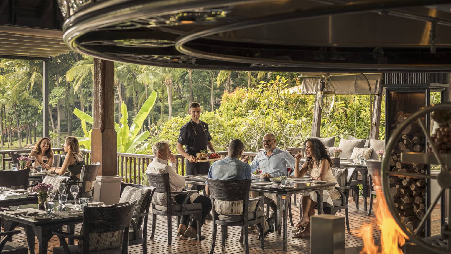 A festive holiday dinner at a restaurant with people sitting at tables and around a fire pit