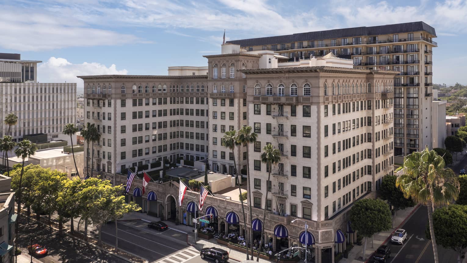 The exterior of a large stone building surrounded by streets and palm trees.